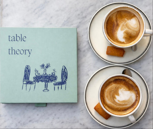 Book titled 'table theory' with two cups of coffee on a marble surface